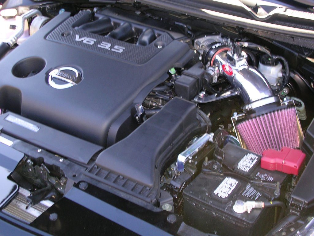 A close-up of a car engine featuring a red air filter and a sleek black hood.