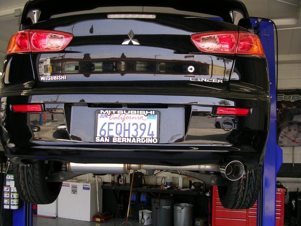 A car is elevated on a hydraulic lift in a garage, showcasing the underside for maintenance or inspection.
